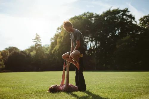 Couple in park practising pair acro yoga